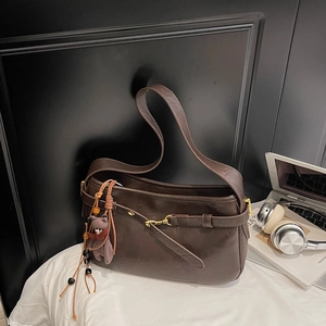 Détail du sac à bandoulière vintage marron foncé avec finition polie et breloque ours
