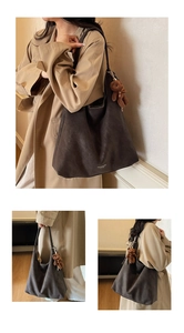 Detail view of large dark brown leather tote bag with a cute plush bear charm