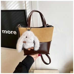 Detailed shot of two-tone bucket bag with glossy brown finish and plush rabbit charm