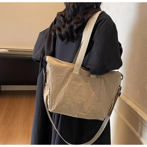 Detail view of beige nylon tote bag featuring adjustable strap and drawstring side pocket