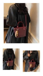Dettaglio della borsa tote intrecciata bordeaux con ciondolo in legno e tracolla lunga