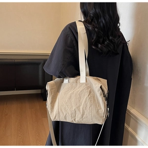 Detail view of the beige tote bag showing side pocket design and fabric texture