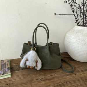 Détail du sac seau mat vert vintage avec un joli porte-clés en peluche lapin blanc