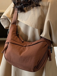 Brown nylon crescent shoulder bag shown on model with stylish khaki trench coat