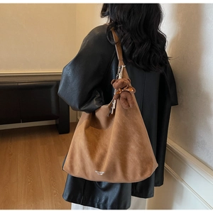 Macro shot of brown suede hobo bag texture with brand logo and plush bear pendant detail