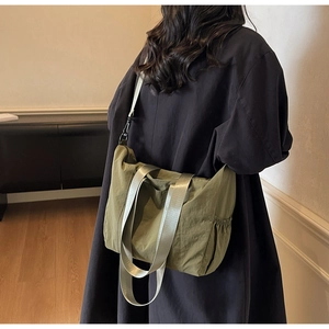 Detail of army green nylon tote bag featuring adjustable shoulder strap and side pocket