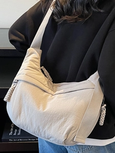 Large beige canvas crescent bag with wide strap worn as crossbody for casual commute