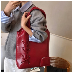 Detail view of large red PU leather tote bag with lace-up decor and small coin purse attached
