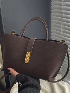 Brown leather tote bag with gold metal buckle and shoulder strap for commute