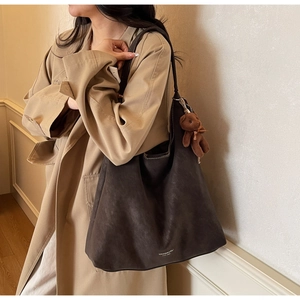 Detail of dark brown matte tote bag featuring fine shoulder straps and a plush bear pendant