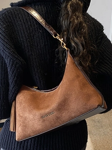 Minimalist brown suede crescent underarm bag with decorative leather tassels and gold hooks