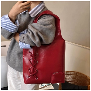 Close-up of burgundy leather tote bag with unique cross-lacing detail and small pouch