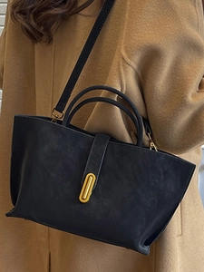 Large capacity black tote bag with gold buckle on model in camel wool coat