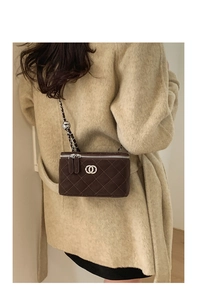 Detailed view of dark brown quilted chain box bag on model in a beige coat