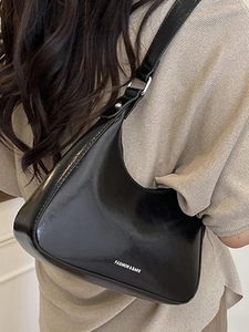 Fashionable black glossy crescent shoulder bag with metallic buckle and white text