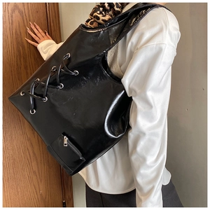 Detail of black glossy tote bag featuring side eyelet lacing and a detachable coin pouch