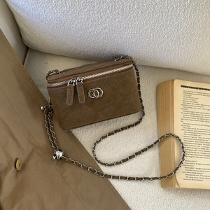 Detailed macro view of brown suede quilted texture and metal interlocking logo on box bag