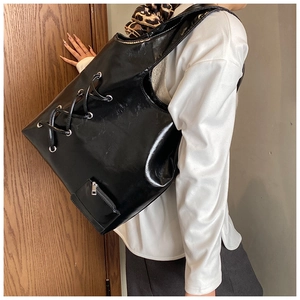 Detail view of black large capacity shoulder bag featuring lace-up design and small pouch