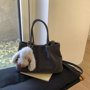 Détail du sac cabas en daim gris foncé avec breloque lapin et ferrures en laiton poli
