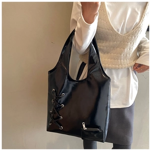 Detail view of large black woven tote bag with side lace-up eyelets and mirror finish