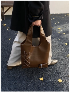 Detailed view of the dark brown leather tote bag with cross straps and silver zippers