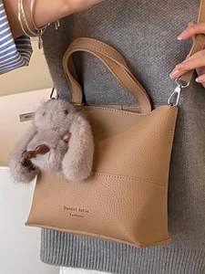Khaki pebbled leather bucket bag with plush rabbit charm and crossbody strap