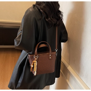 Modella che indossa una borsa a secchiello intrecciata marrone con tracolla in pelle