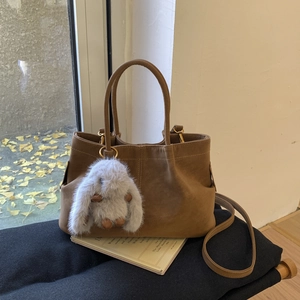 Détail du sac seau vintage en daim marron avec pendentif lapin et bandoulière fine