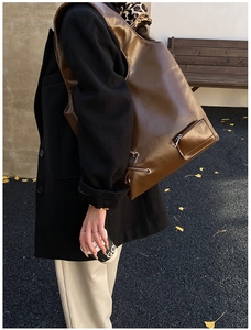 Detail of dark brown PU leather tote bag with metal eyelet drawstring and side zip pocket