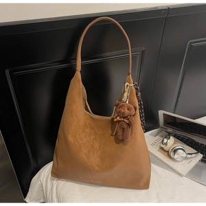 Detailed side view of a large brown suede hobo tote bag with a cute bear charm for work