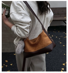 Detail of vintage brown textured crossbody bag with plush rabbit charm in autumn setting