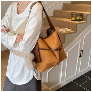 Detail of ginger yellow bucket bag with pleated texture and cute rabbit plush charm