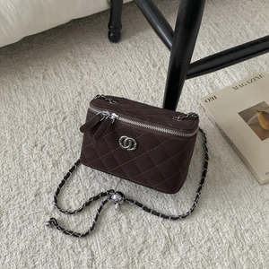 Close-up of brown quilted box bag with silver chain strap and velvet-like finish