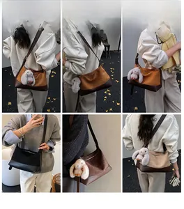 Detail view of large capacity crossbody bag with plush rabbit charm and wide strap