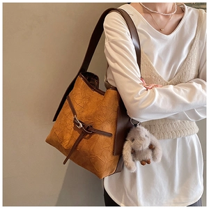 Macro shot of stylish camel bucket bag featuring pleated texture and cute rabbit charm