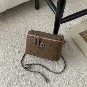 Detail of caramel brown quilted vanity case with silver double ring logo and chain strap