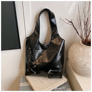 Detail of glossy black tote bag with side lacing and metallic zipper pocket