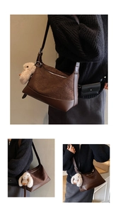 Detail of dark brown tote bag with pleated texture, leather panels, and plush bunny charm