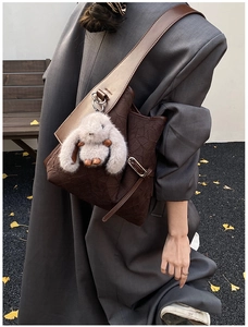 Detail of dark brown bucket bag with wrinkled texture and plush rabbit charm