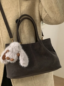 Sac seau rétro gris anthracite avec charme lapin en peluche et deux poignées sur manteau beige