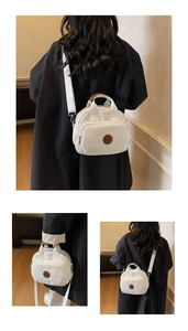 Detail showing white canvas crossbody bag with brown handles and a round logo patch