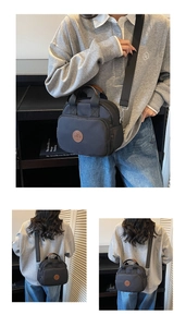 Detail of black nylon crossbody bag with brown leather handle and adjustable strap
