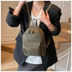 Detail view of mini olive green leather backpack with gold zippers on a female model
