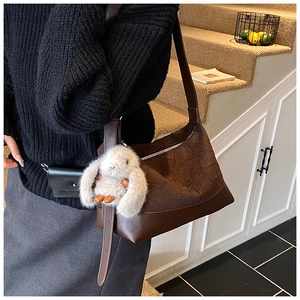 Detail of vintage brown tote bag with wrinkled texture, rabbit charm, and mini pouch