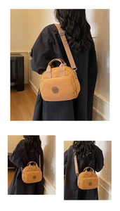 Close-up of yellow canvas crossbody bag featuring front zipper pocket and round leather logo