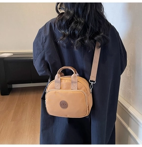 Detail showing ginger nylon crossbody bag on model back for size scale and fit