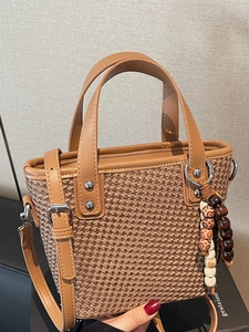 Borsa tote intrecciata a mano color marrone con manici in pelle e ciondolo etnico