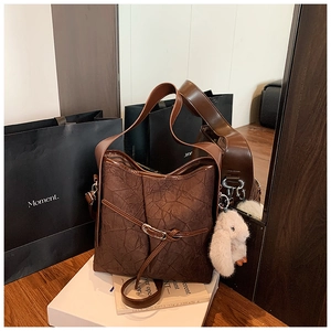 Close-up of brown pleated leather bucket bag with a cute white bunny plush pendant