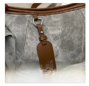Gros plan d'un sac en sergé gris avec garniture en cuir marron et étiquette pendante