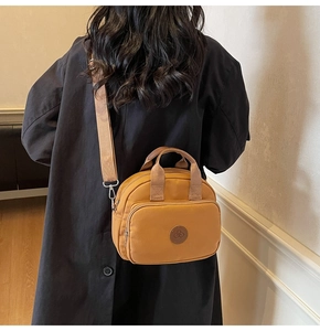 Model wearing a bright yellow nylon crossbody bag with dual handles and wide shoulder strap